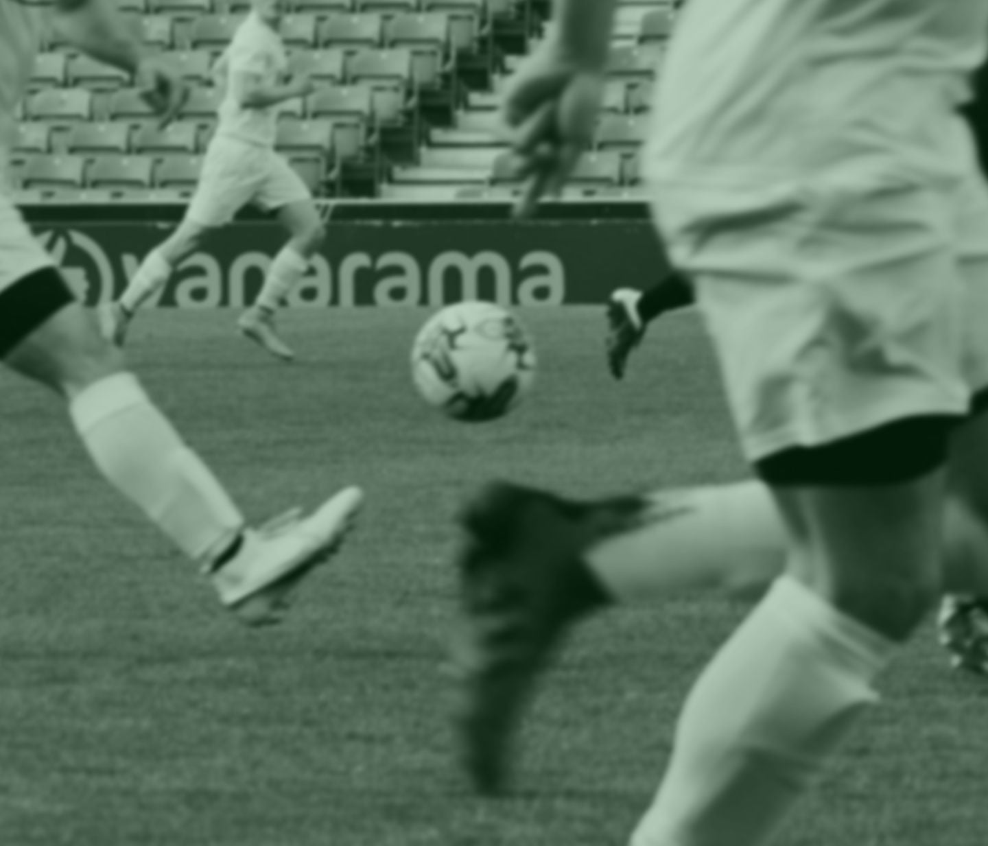 Blurred green-tinted photo of players on the pitch